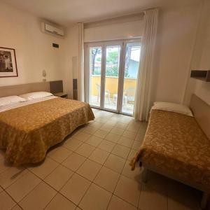 a hotel room with two beds and a balcony at Hotel Furga B&B in Cervia