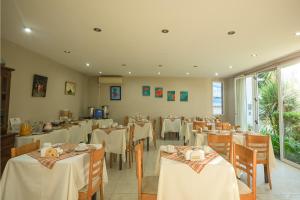 a restaurant with tables and chairs with white tablecloths at Aguas Claras Hosteria in Santa Rosa de Calamuchita