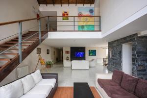 a living room with a white couch and a staircase at Aguas Claras Hosteria in Santa Rosa de Calamuchita