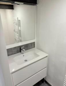 a white bathroom with a sink and a mirror at L'escale les pieds dans l'eau in Barbâtre