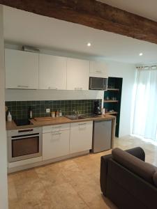 a kitchen with white cabinets and a couch in a room at Studio cosy in Champs