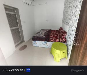 a small room with a bed and a yellow stool at Hotel karishna palace in Rīngas