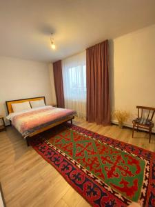 a bedroom with a bed and a rug and a window at Agyn guest house in Karakol