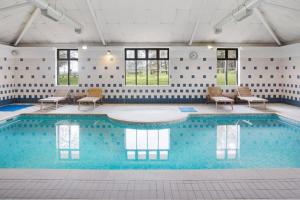 a large swimming pool with chairs and tables in a building at Gateway Mews - Self Check-In, Self-Catering Apartments Near EMA in Kegworth