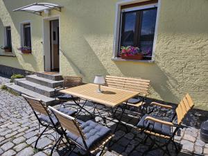 a wooden table and chairs in front of a building at Ferienwohnung Schindler in Nittenau +10 photos