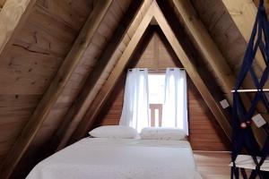 a bed in a room with a window at Chalé Primavera Rosa com piscina in Penha +59 photos