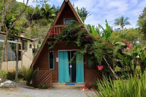 a house with a thatched roof with flowers at Chalé Primavera Rosa com piscina in Penha