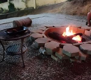 a brick fire pit with a pan on a table at Chalé Primavera Rosa com piscina in Penha