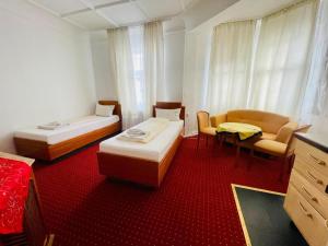 a room with two beds and a couch and a chair at Pension De Lux Augsburg in Augsburg