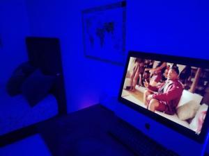 a computer monitor in a blue room with a woman sitting on a couch at chambre pour 2 sidi maarouf in Casablanca