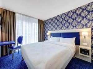 a hotel room with a large bed and a desk at ibis Styles Rastatt Baden-Baden in Rastatt +54 photos
