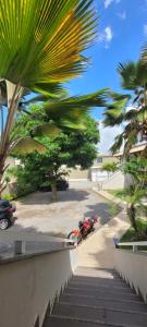 a palm tree and a motorcycle parked on a sidewalk at BRISAS DO FAROL casa 208 in Salvador