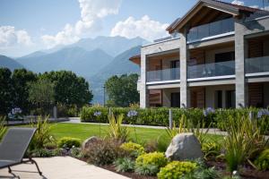 a building with a garden with mountains in the background at Lago Dorato Luxury Apartments - Lake Como View in Colico