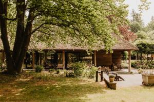 a log cabin with a tree in the yard at B&B Mollenvlied Veluwe in Vaassen