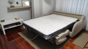 a small bed in a room with a table and a bedskirtspectspectspects at Apartamento turístico CasacheloCangas en el corazón de Cangas, PLAYAS, CIES,VIGO in Cangas de Morrazo