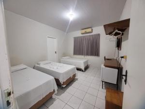 ein Zimmer mit zwei Betten und einem Fernseher in der Unterkunft Hotel Bianchi in Primavera do Leste