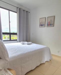 a bedroom with a white bed and a window at Apto 4 andar com vista incrível para piscina in Lucas do Rio Verde