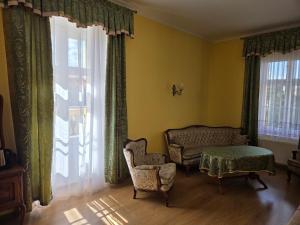 a living room with a couch and a table and windows at Pałac Makowice in Świdnica