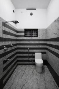 a bathroom with a toilet and black and white stripes at Varkalite homestay in Varkala +5 photos
