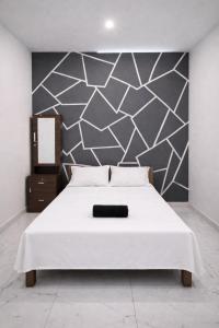 a bedroom with a white bed with a black and white wall at Varkalite homestay in Varkala