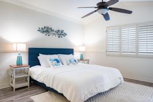 a bedroom with a bed with a blue headboard and a ceiling fan at Luxe 2-Story Oasis with Private Pool & Backyard in Laguna Niguel