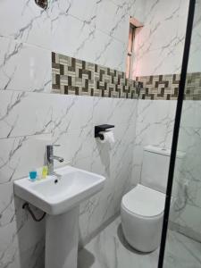 a white bathroom with a toilet and a sink at ROSES REGENCY HOTEL AND SUITES in Abuja +40 photos