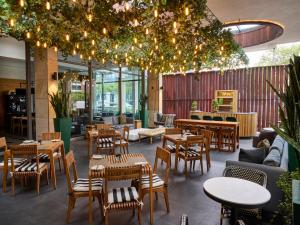 a restaurant with tables and chairs and lights at Century City Hotel Urban Square in Cape Town