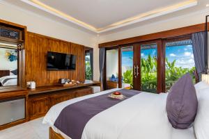 a bedroom with a large bed and a television at Svadarma Bali Villa by Dhananjaya Hospitality in Darmasaba