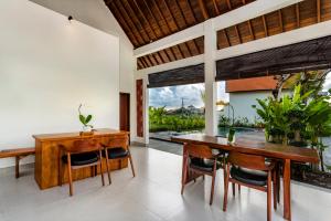 a dining room with a wooden table and chairs at Svadarma Bali Villa by Dhananjaya Hospitality in Darmasaba