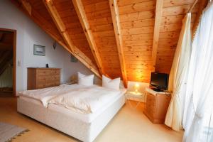 a bedroom with a white bed and a television at Gästehaus Merk Merk Gbr in Immenstaad am Bodensee