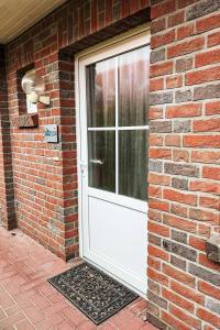 a white door on a brick house with a brick wall at Ferienhaus Seepark 104 in Hoddersdeich