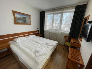 a bedroom with a white bed and a television at Edelweiss Central Hotel in Bansko