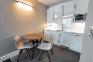 a small kitchen with a wooden table and chairs at Sandman Signature Newcastle Hotel in Newcastle upon Tyne