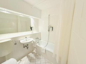 a bathroom with a sink and a tub and a toilet at Hotel Plöner See by Tulip Inn in Plön +29 photos