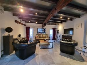 a living room with leather couches and a tv at La Maison de Maurice in Beaune