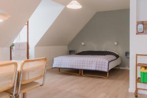 ein Schlafzimmer mit Bett und Stühlen auf dem Dachboden in der Unterkunft Aroma Guesthouse in Ærøskøbing
