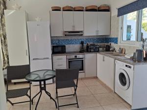 a kitchen with white cabinets and a table and chairs at ATLANTIS Penthouse Apartment with Jacuzzi plus Pool and Sea Views in Peyia