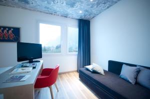 a living room with a couch and a desk with a television at Hotel Luise in Riva del Garda