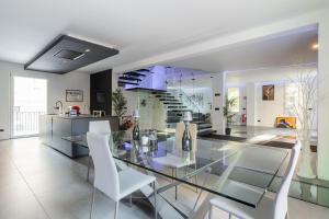 a dining room with a glass table and white chairs at Villa Primodì in Bologna