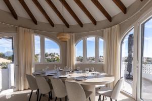 a dining room with a table and chairs and windows at Casa SD in Casas de Torrat