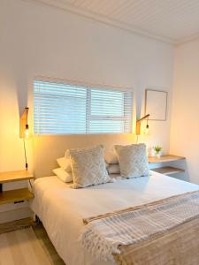 a bedroom with a large bed with white sheets and pillows at Beachouse@Stilbaai in Stilbaai