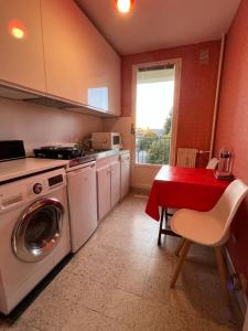a kitchen with a washing machine and a red table at Lemoine in Châteauroux