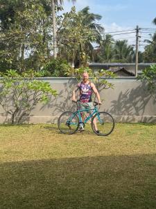 a man is standing next to a blue bike at AMcroos in Negombo
