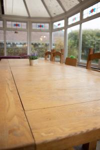 a large wooden table in a room with windows at Stonehenge Farmhouse in Salisbury