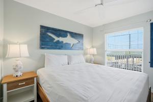 a bedroom with a white bed with a shark painting on the wall at Windward Passage in Fort Myers Beach +37 photos
