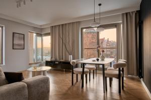 a living room with a table and chairs and a couch at Waterlane Riverside - SPA, Pool, Gym & Parking by Downtown Apartments in Gdańsk