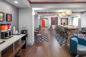 a restaurant with a bar with chairs and a table at Newly Renovated Hampton Inn Omaha West Lakeside in Lane