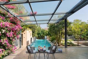 a patio with a pool and chairs and a table at SaffronStays Eden - 3BR vineyard-side pool villa with jacuzzi, farm dining, stargazing deck & lawns for celebrations in Nashik