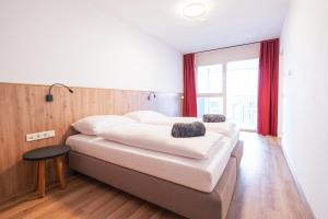 a bedroom with a large white bed with red curtains at KitzSki Living in Kitzbühel