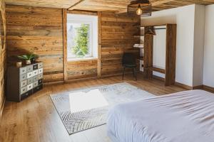 a bedroom with wooden walls and a bed and a chair at La Charbonnière, grand gîte haut-de-gamme avec jacuzzi et sauna in Gérardmer